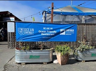 An Ocean Friendly Restaurants Banner hanging outside of a restaurant