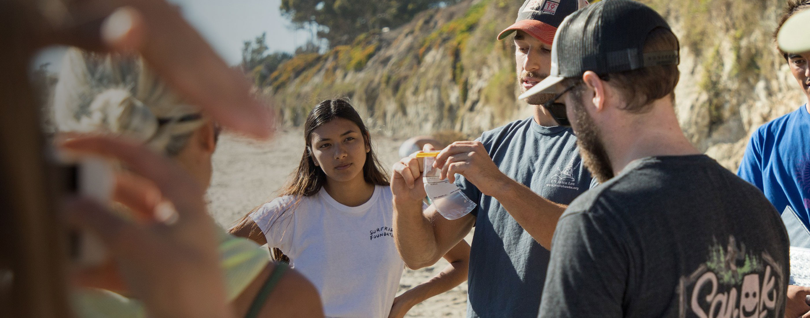 Man holds up small plastic bag in front of young volunteer